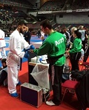 Arzt in grünem Trainingsanzug betreut Karatesportler bei Wettkampf