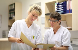 Zwei Schwestern im weißen Kasack schauen in eine Patientenakte